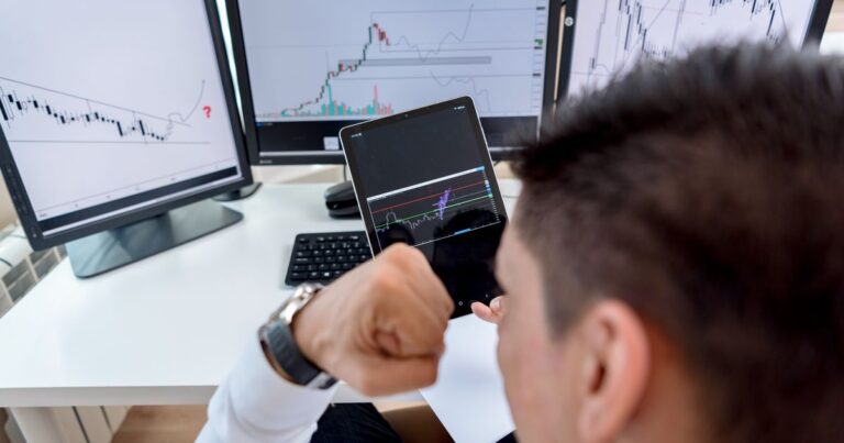 Investidor acompanhando gráficos em vários monitores